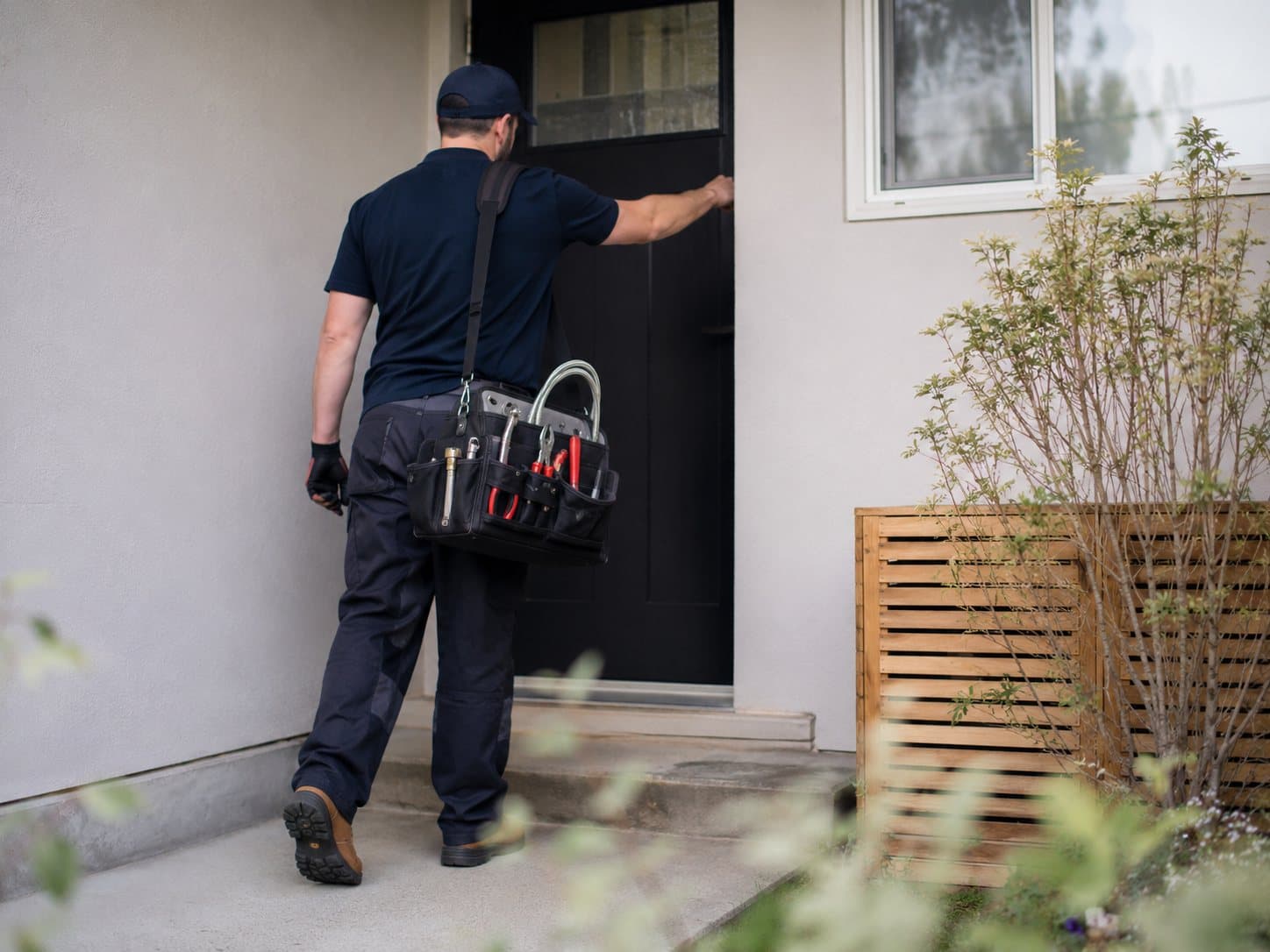 A Maple Ridge plumber walking up to a home's front door with a tool bag